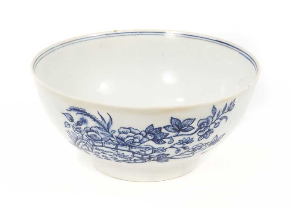 Lot 52 - A rare Isleworth blue and white porcelain bowl, circa 1770, transfer printed with a variation of the Fence pattern on one side, and another Oriental scene verso, with a cornucopia, two birds and a...