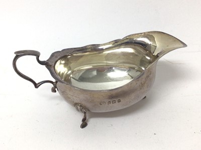 Lot 136 - 1920s silver tea cup with engraved monogram, silver sauce boat, silver vase raised on three legs and silver topped glass jar