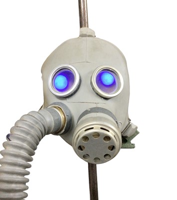 Lot 84 - A pair of child's gas masks converted to table lamps, with blue LED lights fitted behind each eyepiece, 66cm high