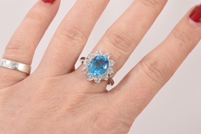 Lot 51 - Blue topaz and diamond cluster ring with an oval mixed cut blue topaz surrounded by ten brilliant cut diamonds