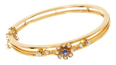 Lot 643 - Late Victorian gold hinged bangle with a blue sapphire and seed pearl flower flanked by two old cut diamonds