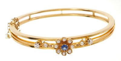 Lot 643 - Late Victorian gold hinged bangle with a blue sapphire and seed pearl flower flanked by two old cut diamonds