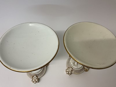 Lot 6 - Set of four 19th century white glazed tazzas, each in the form of a circular dish being held aloft by a putto, the bases decorated in gilt, 24.5cm high