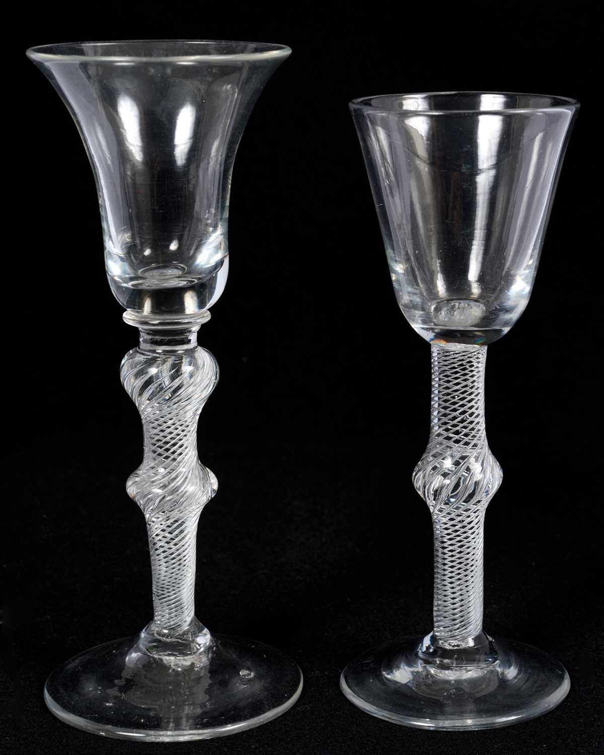 Lot 58 - Two 18th century multi spiral air twist wine glasses, the first with round funnel bowl on a single-knopped stem, the other with bell bowl on a double-knopped stem, 15cm and 16.5cm high