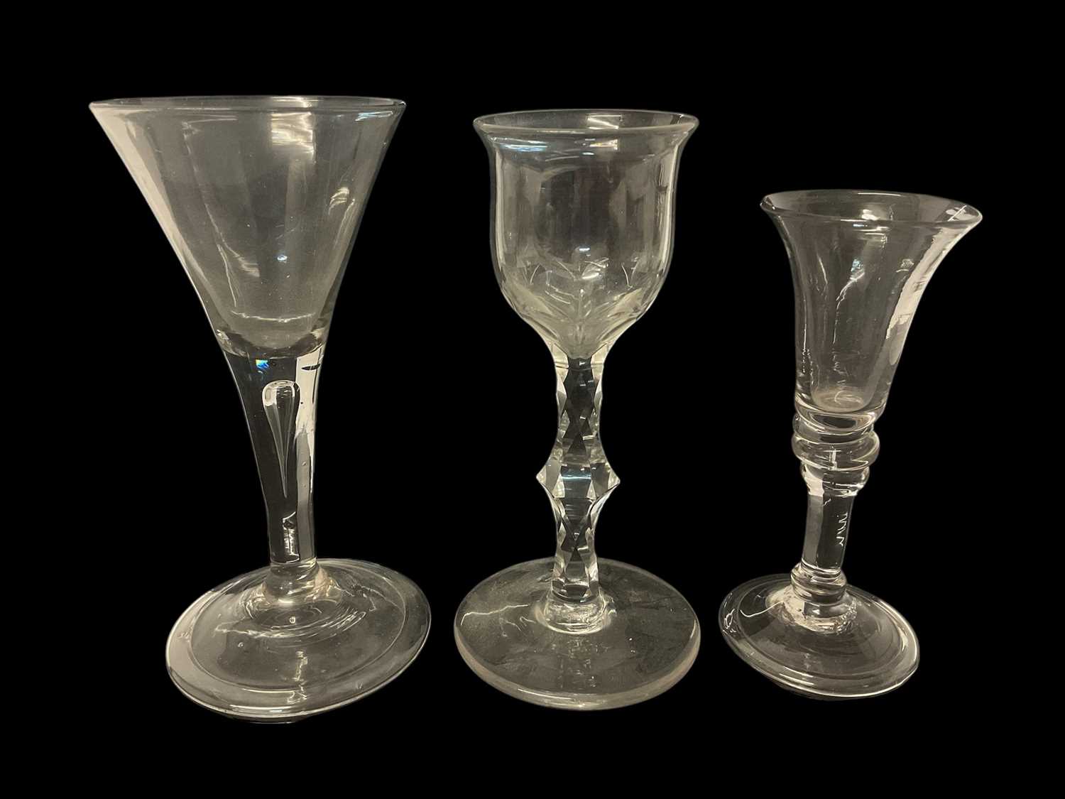 Lot 64 - Three 18th century wine glasses, including one with drawn trumpet bowl and teared stem, one with cut ogee bowl and faceted stem, and one other, 13cm to 15.5cm high (3)