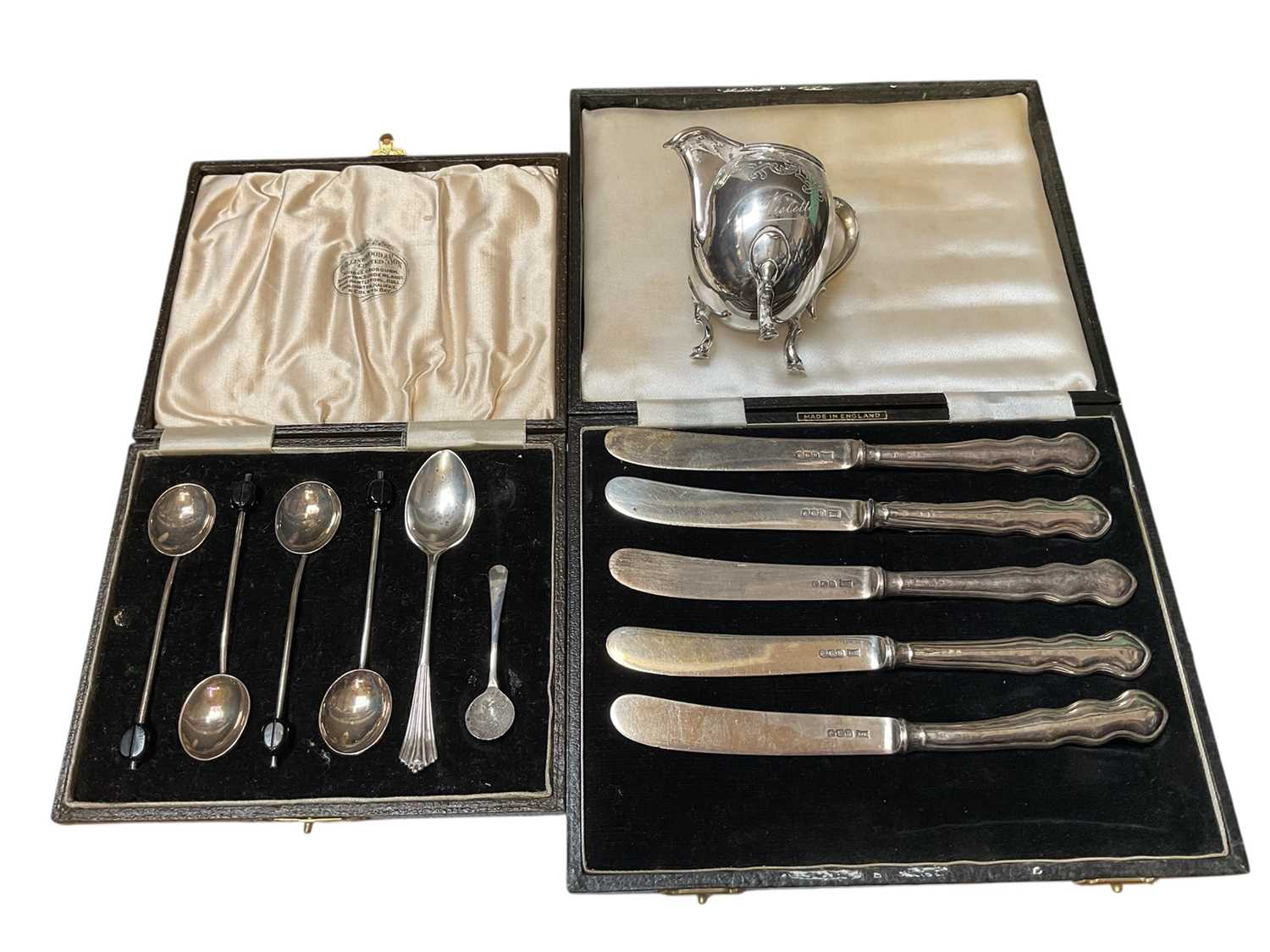 Lot 122 - Five 1930s silver butter knives, various silver spoons and a Continental silver (800) cream jug with engraved decoration