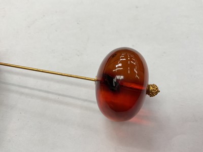 Lot 42 - Victorian amber hat pin with a large polished amber bead terminal on a gilt metal pin, in original fitted case