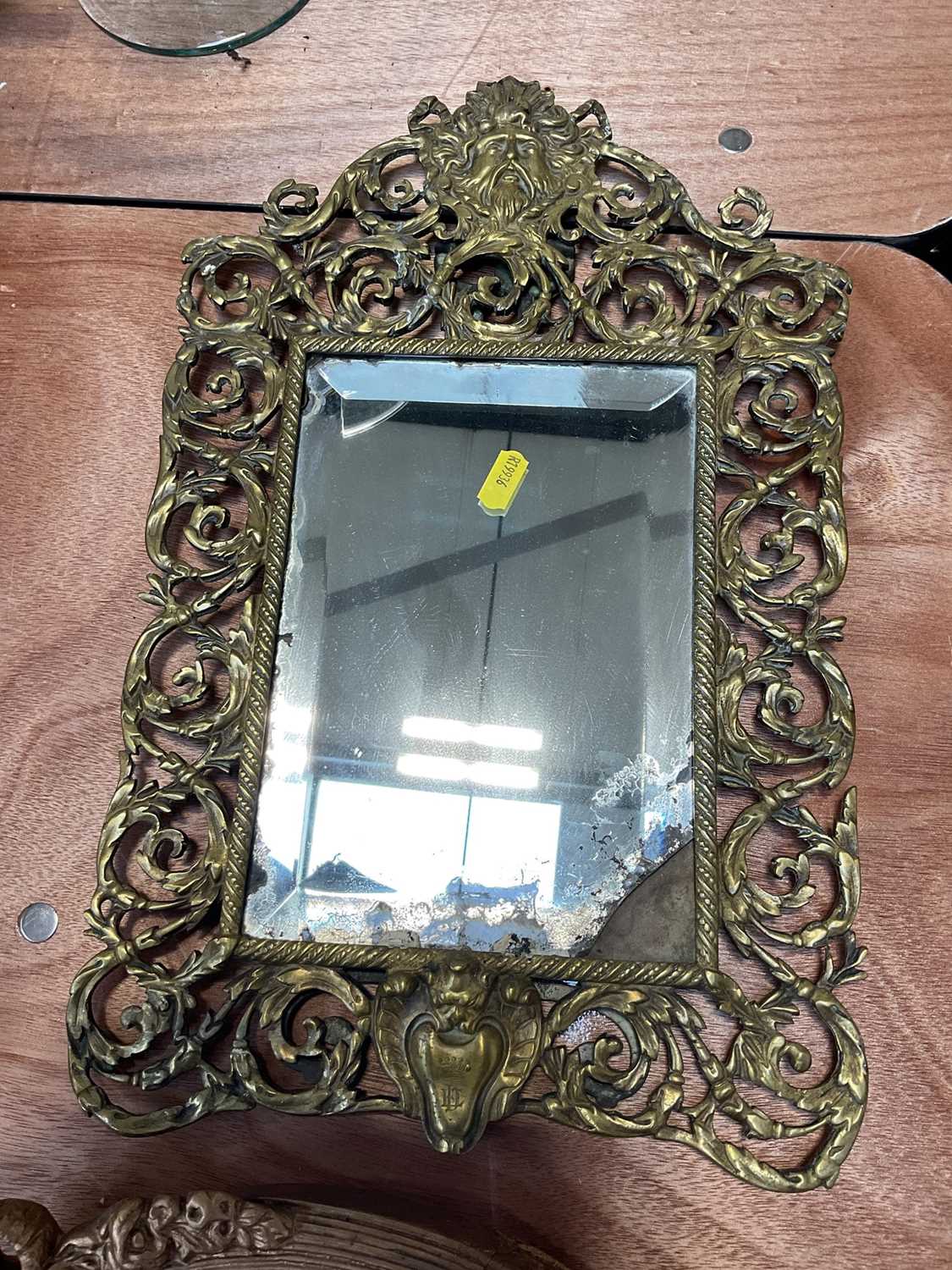 Lot 5090 - Victorian brass easel mirror with mask and scrolling foliage, engraved with a crown and initials, 45cm x 27cm, together with an oval gilt wall mirror (2)