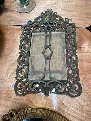 Lot 5090 - Victorian brass easel mirror with mask and scrolling foliage, engraved with a crown and initials, 45cm x 27cm, together with an oval gilt wall mirror (2)