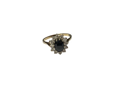 Lot 278 - 9ct gold oval mixed cut blue sapphire ring with a border of white synthetic stones, size P