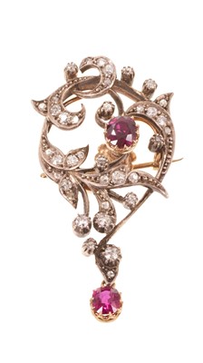 Lot Edwardian Art Nouveau ruby and diamond pendant brooch with an asymmetric floral scroll set with a central mixed cut ruby within old cut diamond scrolls, suspending a further ruby drop, in silver...