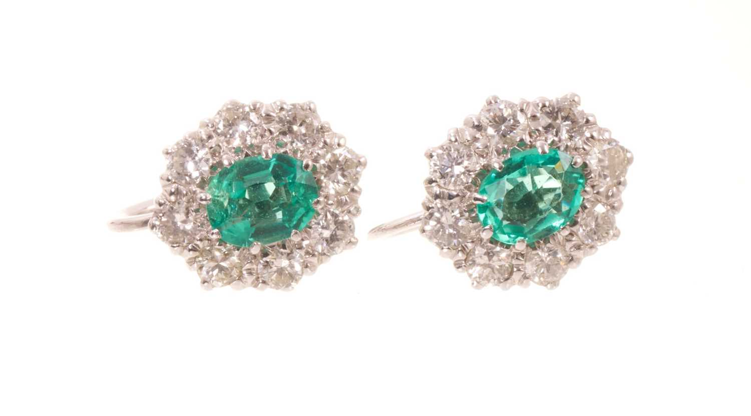 Lot 556 - Pair of emerald and diamond cluster earrings, each with an oval mixed cut emerald measuring approximately 5.8 x 4.6mm, surrounded by a border of eight brilliant cut diamonds in white gold claw s...