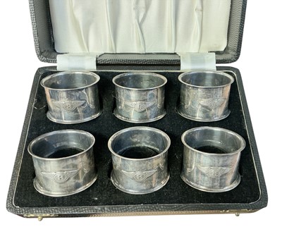 Lot 94 - Set of six 1930s silver plated napkin rings, each mounted with a Bentley winged B logo, in a fitted case