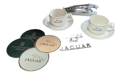 Lot 152 - Jaguar Cars chromium plated leaper mascot, together with a pair of Jaguar branded cups and saucers, E-Type badges, sports bag and leather samples (1 box)