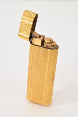 Lot 469 - Cartier gold plated lighter with engine turned decoration, numbered 15660A.