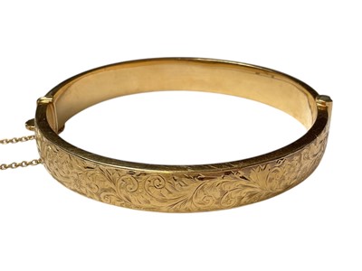 Lot 59 - 18ct gold hinged bangle with engraved floral scroll decoration to one side (Birmingham 1962)