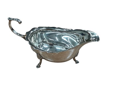 Lot 295 - 1930s silver sauce boat of conventional form, with shaped border and open scroll handle