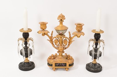 Lot 720 - Garniture of 19th century bronze and ormolu candlesticks, the twin branch example with painted marble panels, the pair with prismatic drops (3)