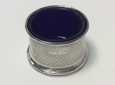 Lot 153 - George V silver three piece cruet set of drum form with engine with removable blue glass liners and matching spoons, (Birmingham 1928), maker Docker & Burn Ltd, pepperette 5.2cm in height, all at a...