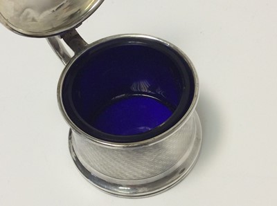 Lot 153 - George V silver three piece cruet set of drum form with engine with removable blue glass liners and matching spoons, (Birmingham 1928), maker Docker & Burn Ltd, pepperette 5.2cm in height, all at a...