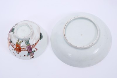 Lot 57 - Lowestoft tea bowl and saucer, painted in the Mandarin style with three figures, one smoking a pipe, within a red overlapping loop border, saucer 12.1cm diameter