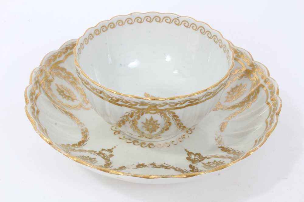 Lot 20 - Worcester fluted tea bowl and saucer, circa 1775-80, decorated in gilt with swags and other patterns, the saucer measuring 14cm diameter