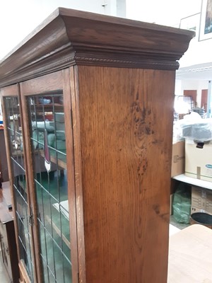 Lot 1025 - Early 20th century oak bookcase/display cabinet with shelved interior enclosed by two tinted and leaded glazed doors, single drawer below on spiral twist supports, 125cm wide, 41cm deep, 181.5cm hi...